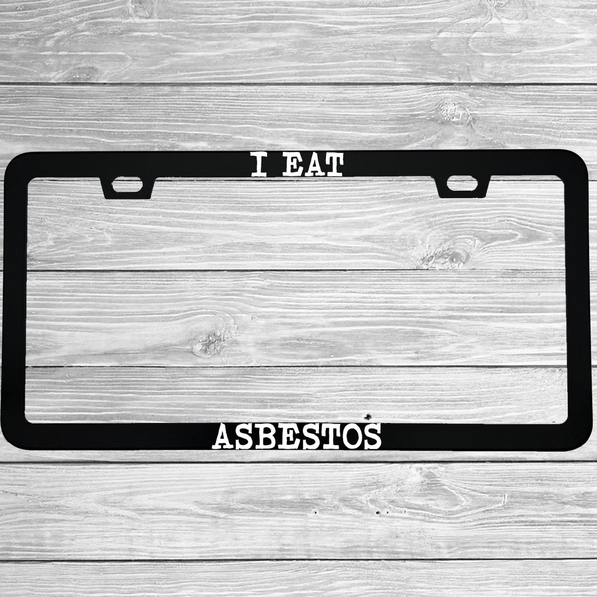 Close-up of "I Eat Asbestos" license plate frame showing fade-proof print quality