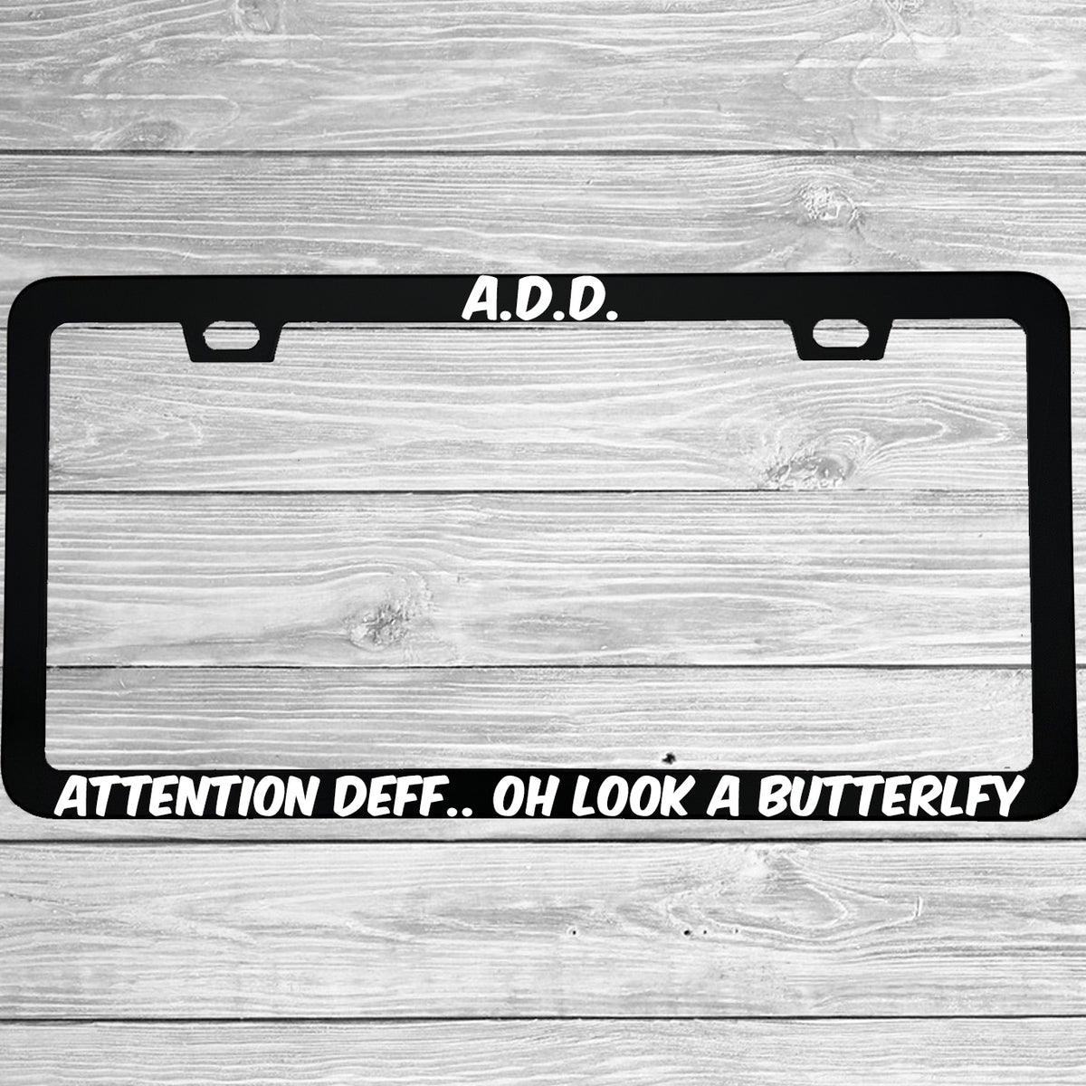 Close-up of "ADD Attention Def Oh Look A Butterfly" license plate frame showing fade-proof print quality