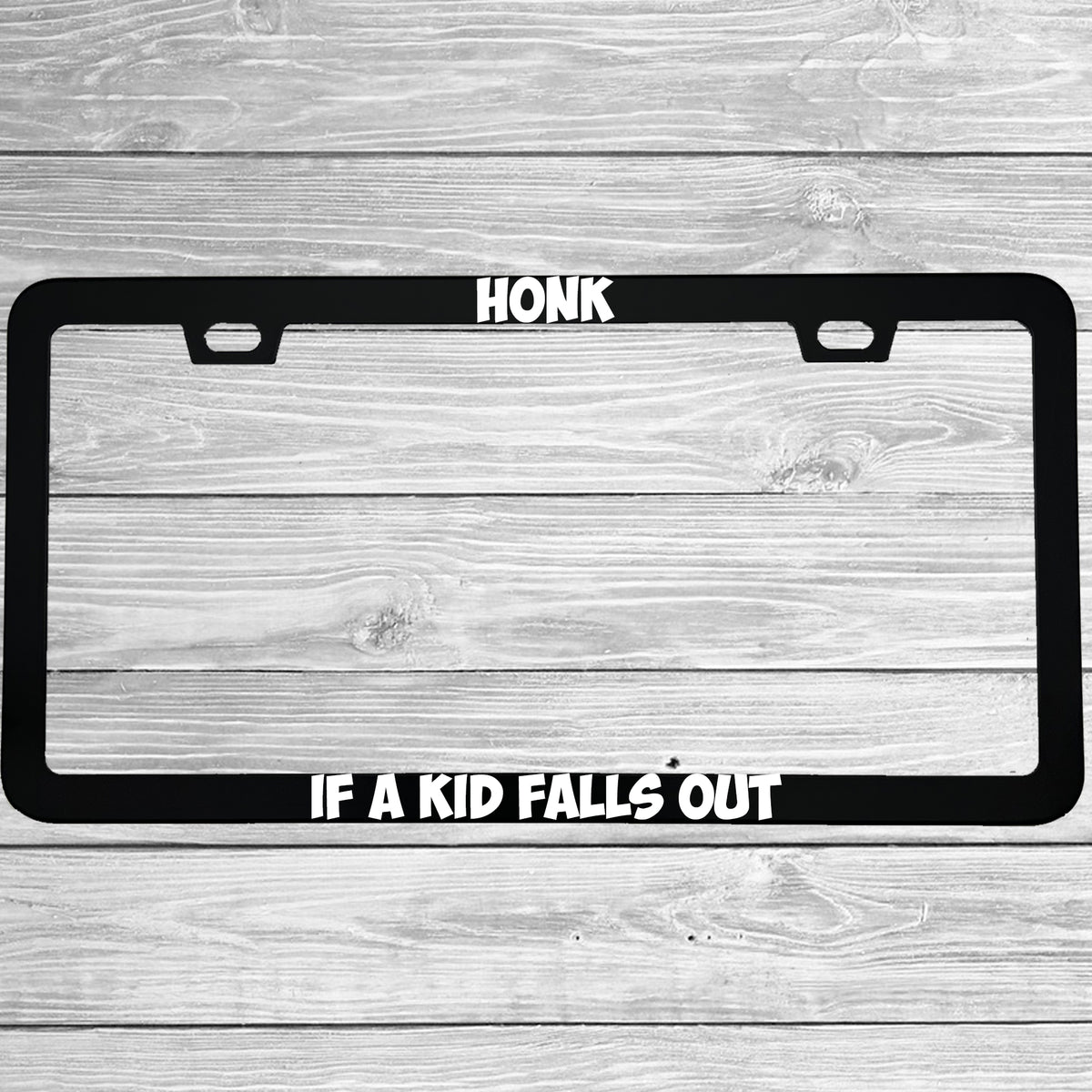Close-up of "Honk If A Kid Falls Out" license plate frame showing fade-proof print quality