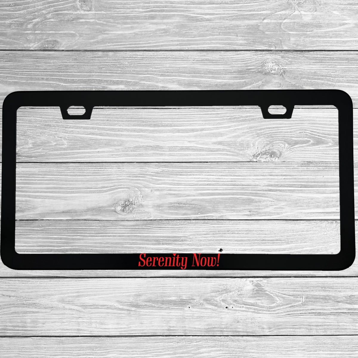 Close-up of "Serenity Now" license plate frame showing fade-proof print quality
