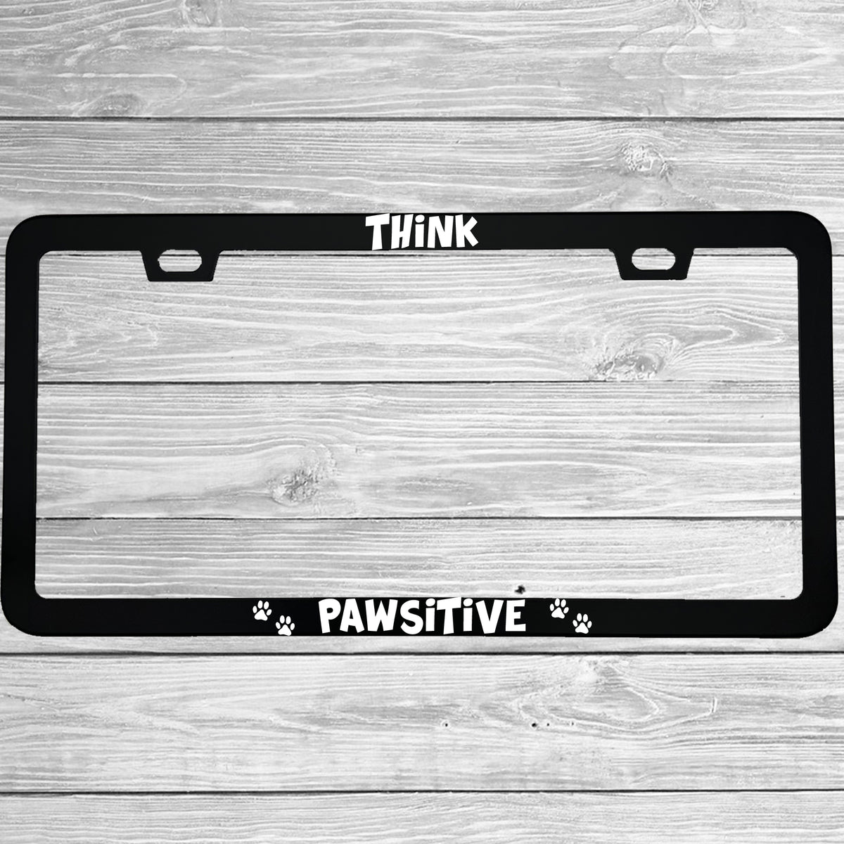 Close-up of "Think Pawsitive (Positive)" license plate frame showing fade-proof print quality
