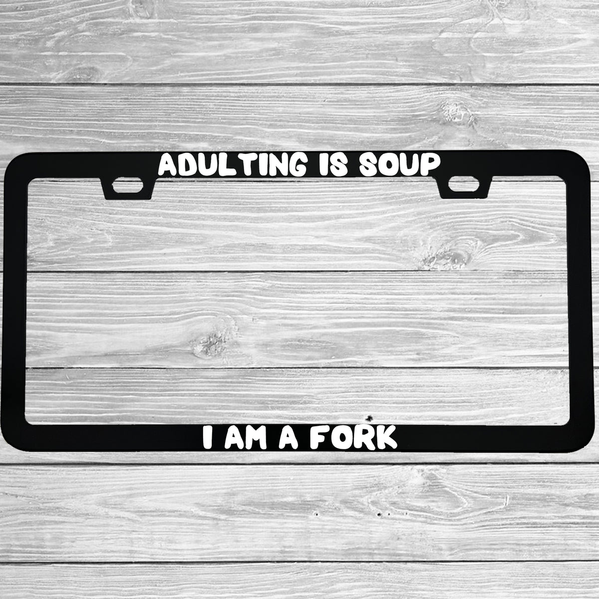 Close-up of "Adulting Is Soup, I Am A Fork" license plate frame showing fade-proof print quality