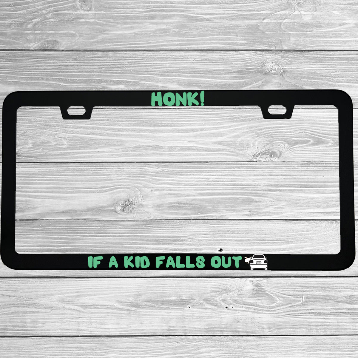 Close-up of "Honk If A Kid Falls Out" license plate frame showing fade-proof print quality