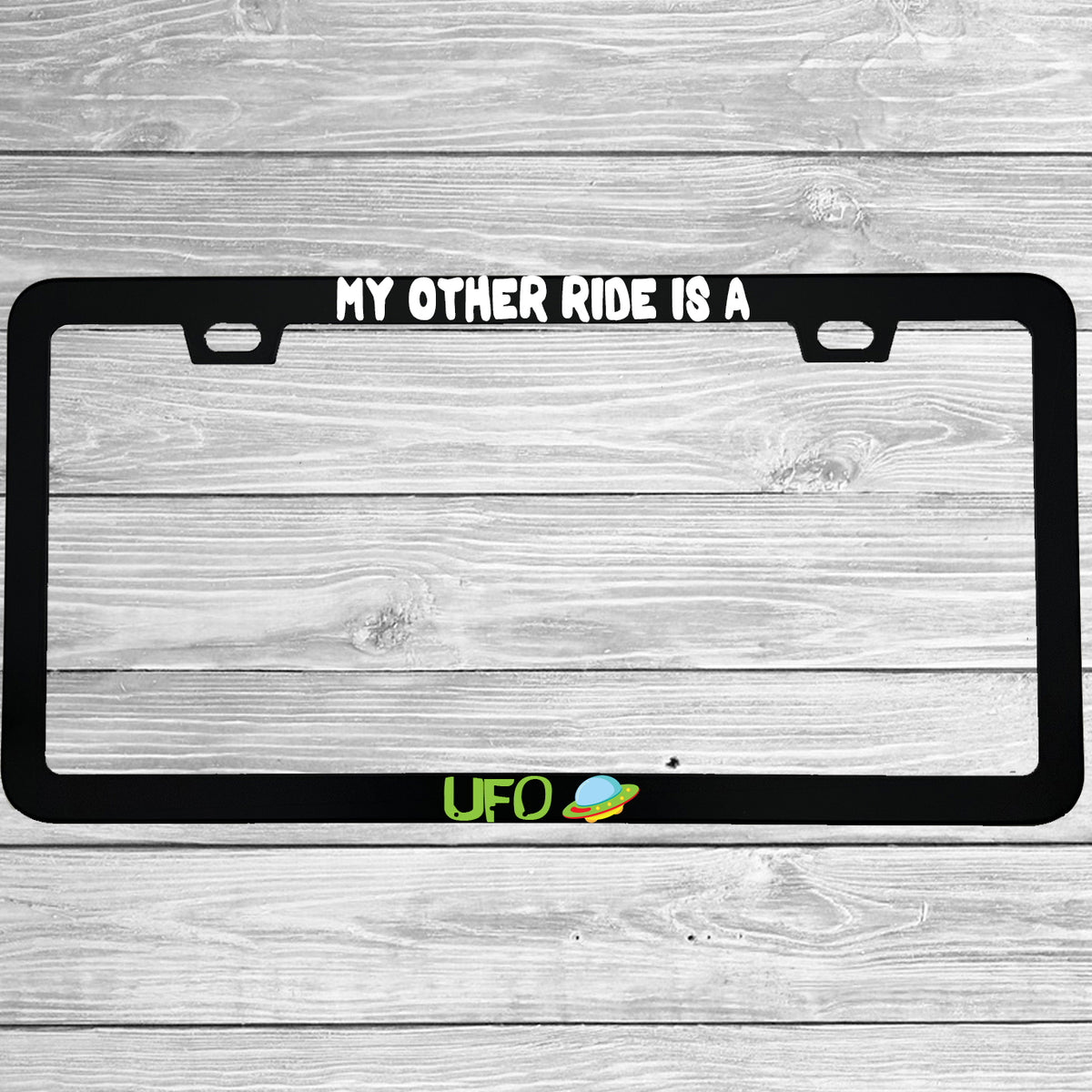 Close-up of "My Other Ride Is A UFO" license plate frame showing fade-proof print quality
