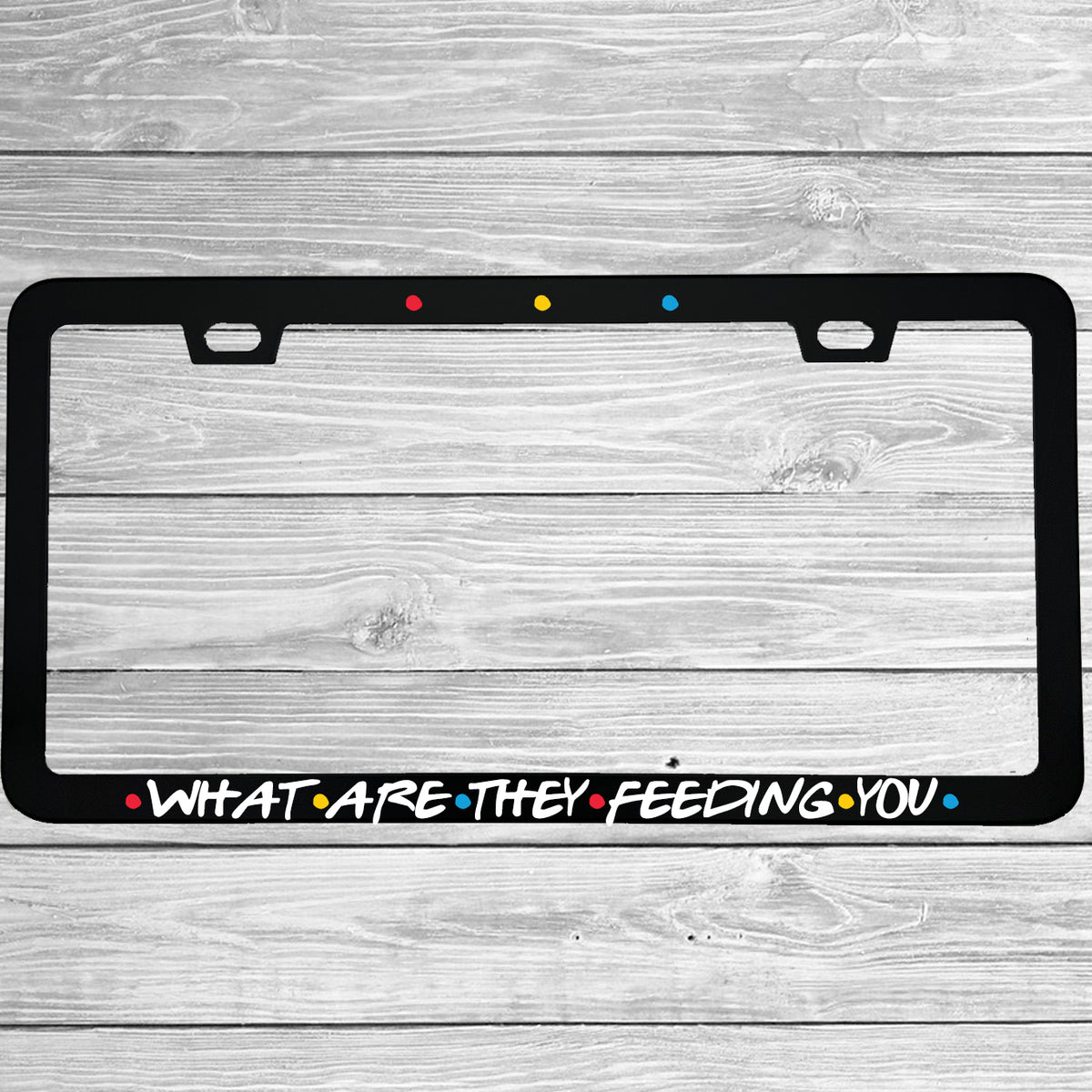 Close-up of "What Are They Feeding You" license plate frame showing fade-proof print quality