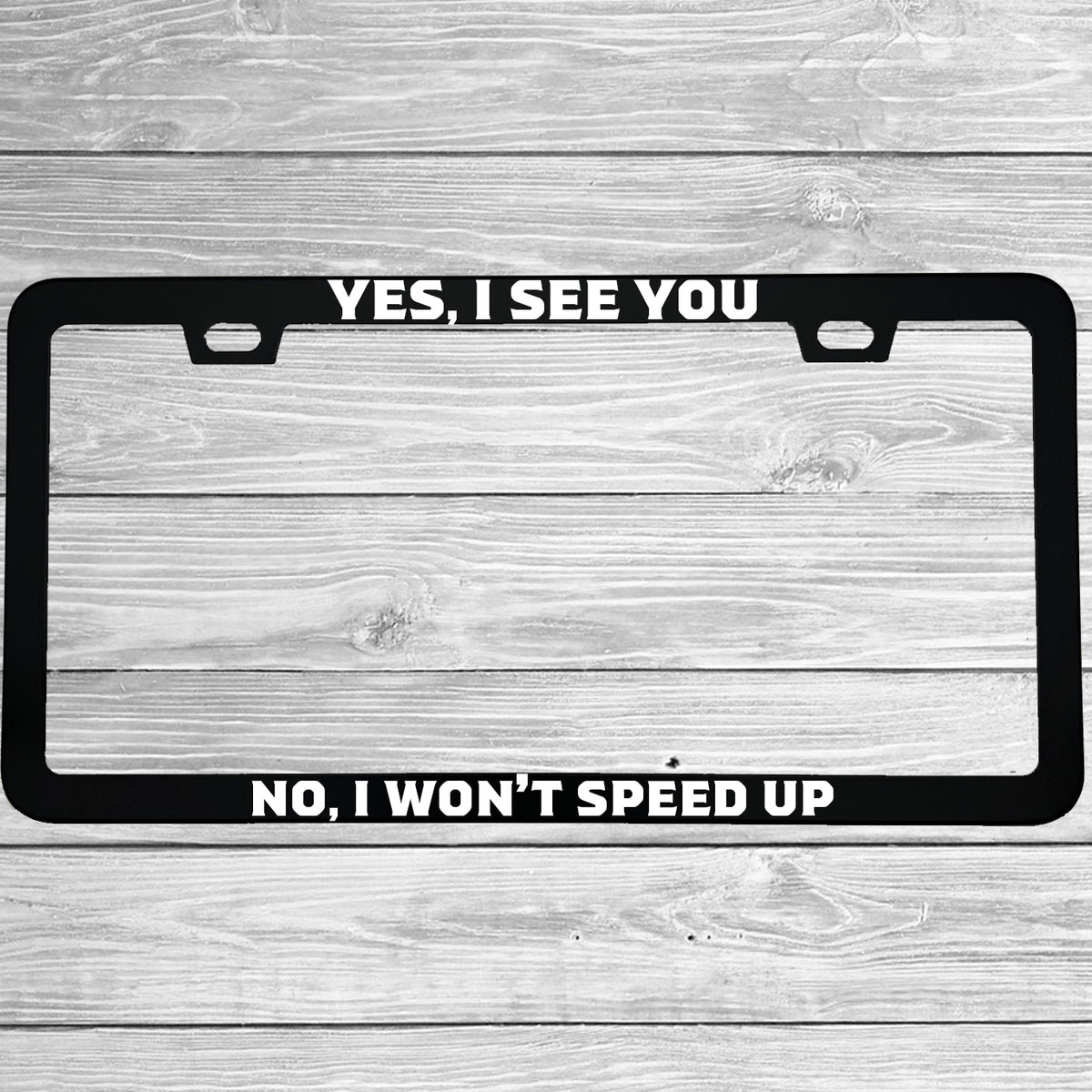 Close-up of "Yes I See You No I Won't Speed Up" license plate frame showing fade-proof print quality